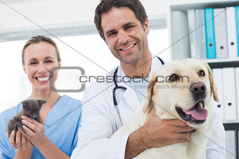 Confident veterinarians with dog and kitten
