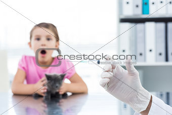 Vet holding syringe with socked girl holding kitten