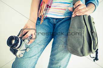 Woman in denim holding camera and shoulder bag