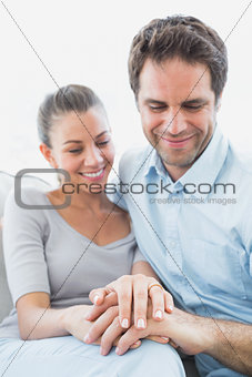 Couple looking at wedding ring on womans finger on the couch