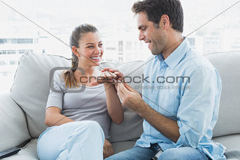 Excited couple getting engaged on their sofa
