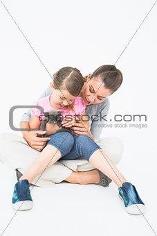 Cute daughter and mother sitting with pet kitten together