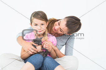 Happy daughter and mother sitting with pet kitten together