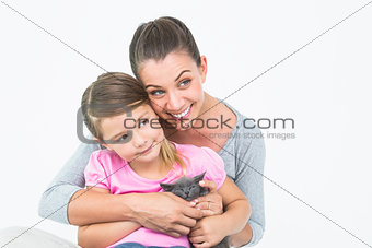 Happy mother and daughter sitting with pet kitten together