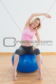 Fit blonde pregnant woman sitting on exercise ball