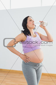 Pregnant woman drinking from bottle of water