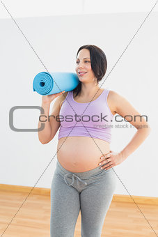 Happy pregnant woman holding exercise mat