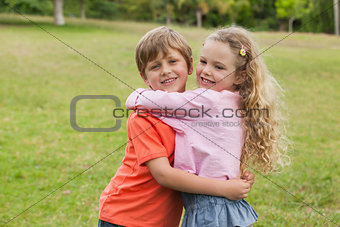 Two smiling kids hugging at park