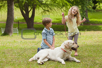 Two happy kids with pet dog at park