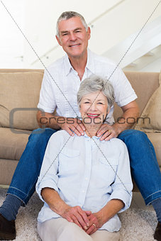 Man giving his relaxed senior wife a shoulder rub smiling at camera