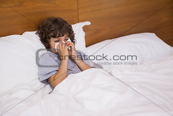 Little boy suffering from cold as he lies in bed