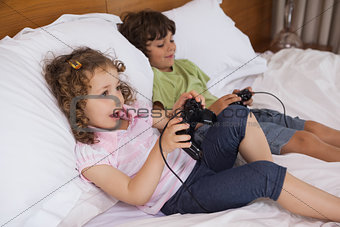 Brother and sister playing video games in bedroom