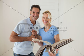 Portrait of a happy couple with color book in new house