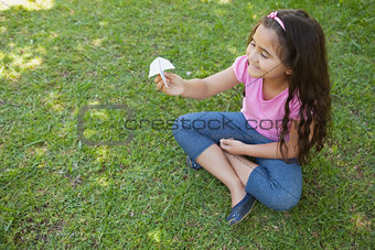 Happy girl playing with a paper plane at park