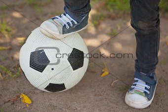 Low section of boy with leg on football at park
