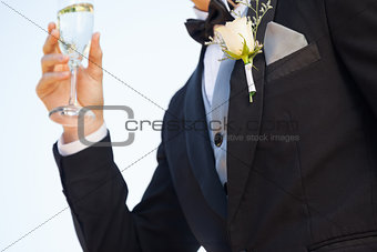 Mid section of flowers on lapel of male as he holds champagne glass