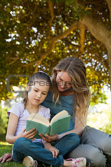 Mother and daughter reading a book at park