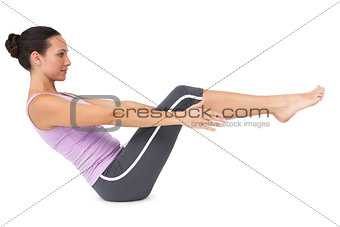 Side view of a fit young woman doing the boat pose