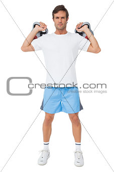 Full length portrait of a fit man lifting kettlebells