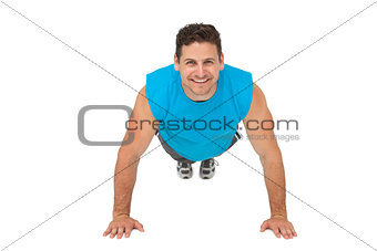 Portrait of a smiling young man doing push ups