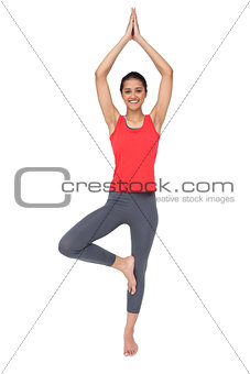 Full length of a fit smiling woman standing in tree pose