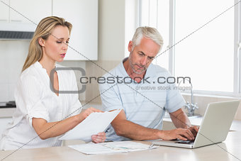 Worried couple working out their finances with laptop