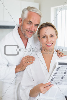 Happy couple reading newspaper together in bathrobes
