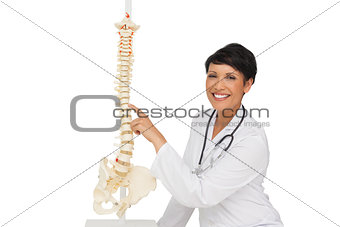 Smiling female doctor pointing at skeleton model
