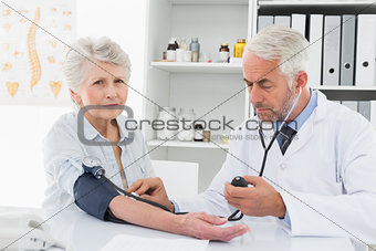 Doctor taking blood pressure of his retired patient