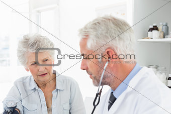 Doctor taking the blood pressure of his retired patient