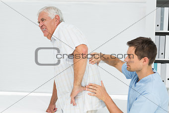 Male physiotherapist examining senior mans back