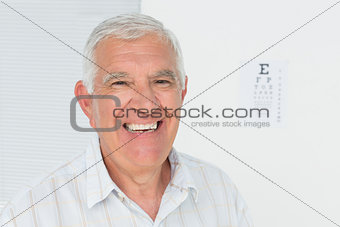 Smiling senior man with eye chart in the background