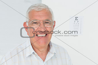 Portrait of a smiling senior man with eye chart in background