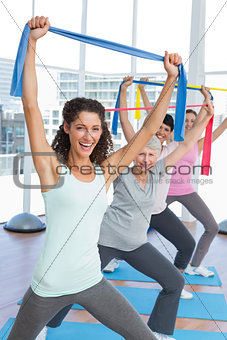 Class holding up exercise belts at yoga class