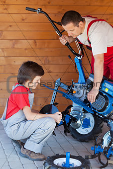 Boy helps his father mounting a cultivator machine