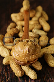 peanut butter in a wooden spoon with whole nuts
