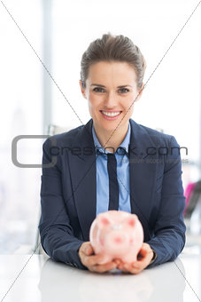 Portrait of happy business woman holding piggy bank