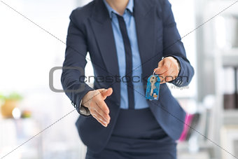 Closeup on happy business woman giving keys and stretching hand 