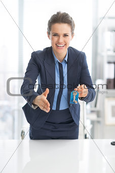 Happy business woman giving keys and stretching hand for handsha