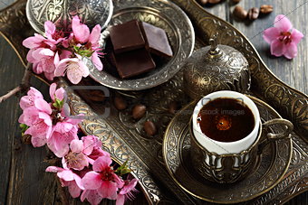 Turkish coffee, chocolate and branch with pink flowers.