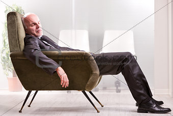 mature businessman asleep on an armchair
