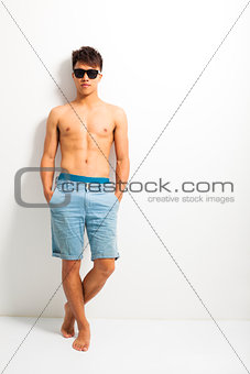 young man wear a sunglasses and standing near the wall