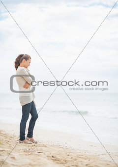 Thoughtful young woman standing on cold beach