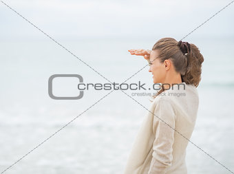 Young woman looking into distance while standing on cold beach s