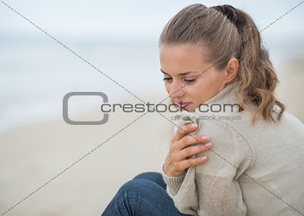 Portrait of calm young woman sitting on cold beach
