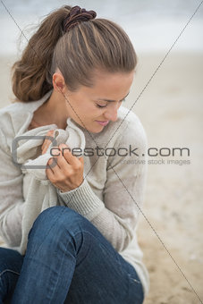 Happy woman sitting on cold beach