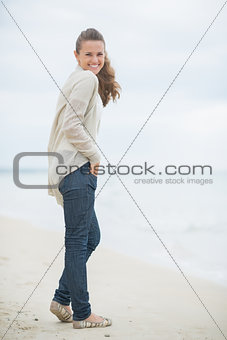 Full length portrait of happy young woman on cold beach