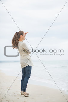 Full length portrait of young woman on cold beach looking into d