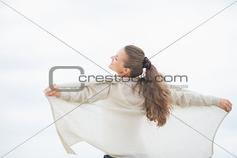 Young woman on cold beach rejoicing. rear view
