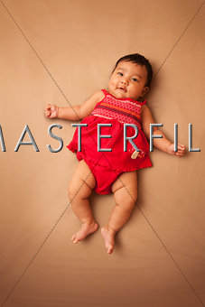 Asian infant wearing red dress on tan background